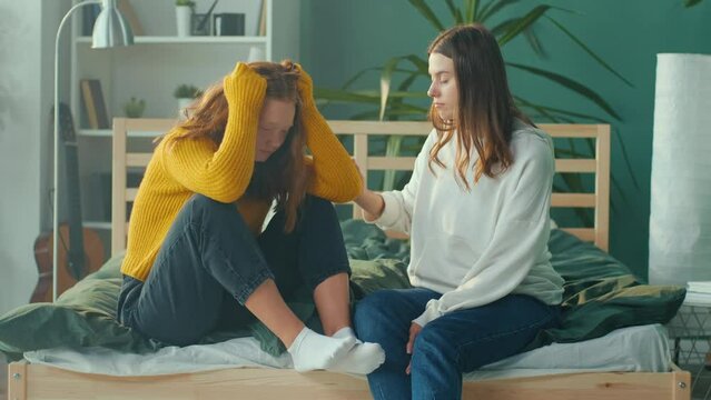 Stressed Red Haired Teenage Girl Emotionally Crying on Couch While Friend Sitting near and Trying to Calm her Down. Friendly Support. Teenage Psychological Trauma, Adolescence Concept. Mental Health.