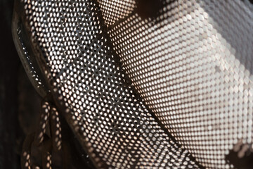 abstract background with metal object similar to a sieve hanging on a wall with sunlight shining...