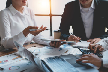 Business people pointing to graphs and charts to analyze market data, balance sheet, accounts, net profit to plan to increase sales. New sales strategies to increase productivity and income.