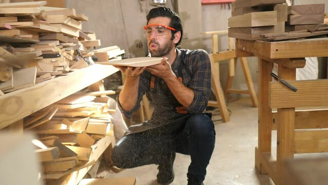 Carpenter man with bearded wearing glasses and working in wood workshop
