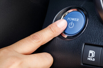 Finger pushing on power button to start keyless ignition hybrid car electro engine