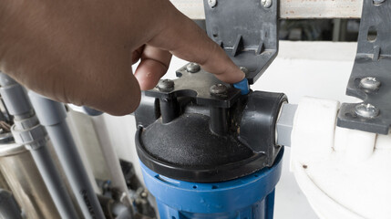 The man pressing the pressure relaease button for replace the  case water filter.