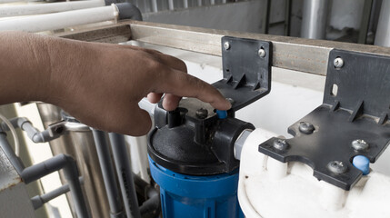 Obraz premium The man pressing the pressure relaease button for replace the case water filter.