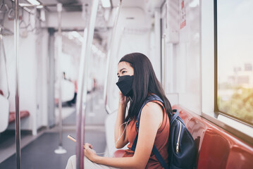 Women wearing face mask and using mobile phone for listening to music in subway train,Safety on public transport concept