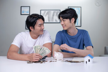 Young happy Asian gay couple saving money to buy a house. LGBT men couple saving money for family and home.