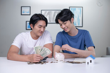 Young happy Asian gay couple saving money to buy a house. LGBT men couple saving money for family and home.