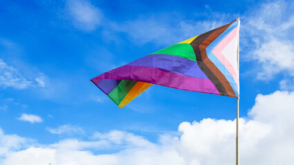 LGBT rainbow flag waving with blue sky in background to enhance LGBTQ+ community around the world