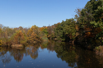 Beautiful Fall foliage around very reflective lake. This picture was taken in the Green Lane reservoir nature center close to Pennsburg in Pennsylvania. The leaves have really pretty Autumn colors.