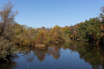 Beautiful Fall foliage around very reflective lake. This picture was taken in the Green Lane reservoir nature center close to Pennsburg in Pennsylvania. The leaves have really pretty Autumn colors.
