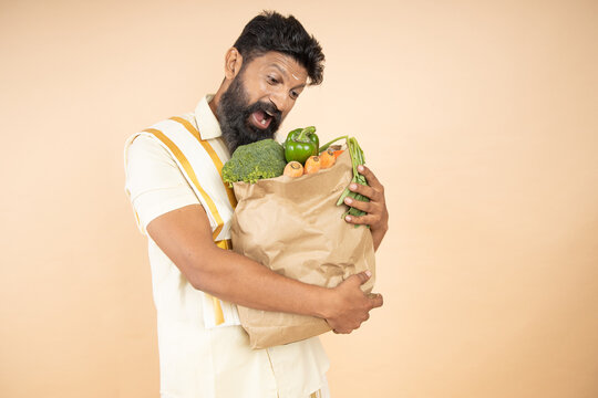 Happy South Indian Man Hold Grocery Paper Bags With Food Isolated On Beige Background. Studio Shot.