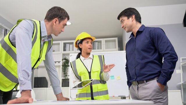 Engineers and competent employer discussing plans and blueprints together with tablet in the office. Concept of team contribution of ideas for engineering project.