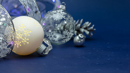 christmas decorations on blue background. glass balls with curling silver ribbon and pine cone.