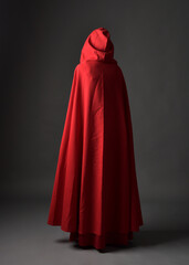 Full length portrait of woman wearing red medieval fantasy costume, flowing hooded cloak. Standing...