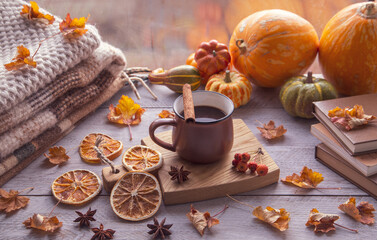Autumn mood, autumn atmosphere. A cup of coffee, pumpkins, knitted warm blankets, books, autumn leaves on the windowsill.
