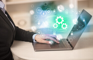 Hands working on laptop with digital icons