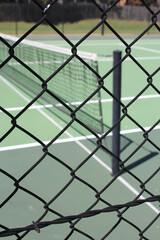 Naklejka premium Abstract view of all weather green tennis court, looking through diamond wire fencing