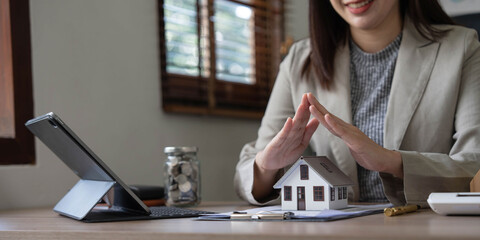 real estate agent use their hands to protect the red roofs, the concept of protecting houses using the gestures and symbols of real estate investors, taking care of credit and contracts.