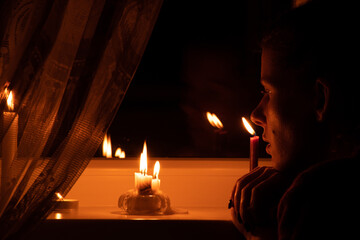 The girl's face put candles on the window in an apartment in Ukraine, Ukraine without electricity...