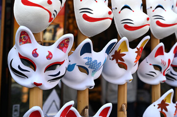 日本のお祭りで狐と猫のお面が並ぶ風景