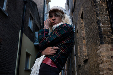 Fototapeta na wymiar Portrait of a confident and tough alternative woman model posing in a narrow street.