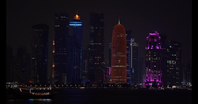 Doha West Bay skyline at night with boat passing by the modern city.