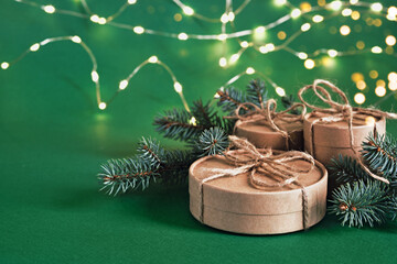 Christmas sustainable round gift boxes and shining garland on green background. Christmas zero...