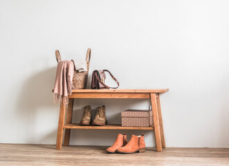 Fototapeta na wymiar Scandinavian style interior . Wooden bench with shoes, a basket with a scarf, a warm blanket - an autumn homely atmosphere in the rustic style hallway room