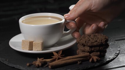 Female hands takes a cup of coffee. Woman warms her hands with hot coffee cup