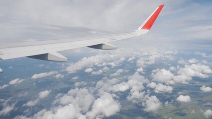 Fototapeta premium Airplane flight. Wing of an airplane flying above the clouds with sky. View from the window of the plane.