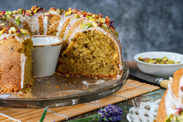 Fragrant Persian love cake decorated with with vanilla icing, crushed pistachio nuts and dried rose petals