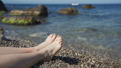 Legs of girl lying on the beach on a sunny day. Close up Slow motion