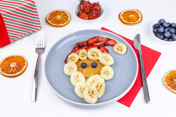 New Year or Christmas food for kids. Pancakes with banana and strawberries