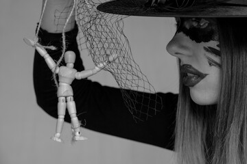 The witch holds a wooden doll of a man on the ropes, manipulation of people and power, magic and...