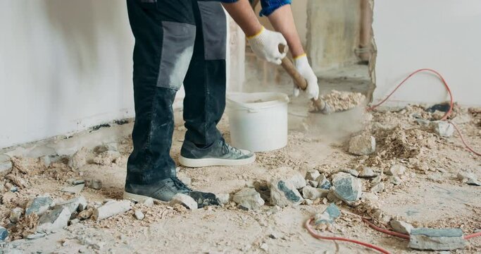 Busy builder collecting construction debris with a shovel. Home renovation demolition of walls.