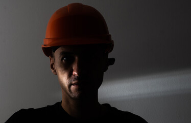 Dirty face of coal miner on a black background. Head of tired mine worker in a hard hat.