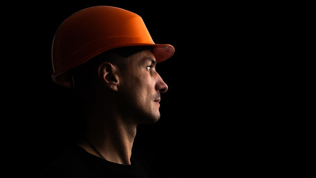 Dirty face of coal miner on a black background. Head of tired mine worker in a hard hat.