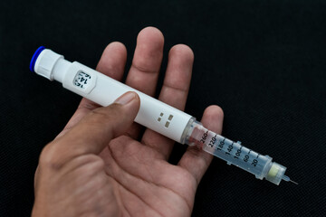 Naklejka premium Insulin pen isolated on black background. Medical devices are used for self-injection for the treatment of diabetes. World diabetes day and health care concept.