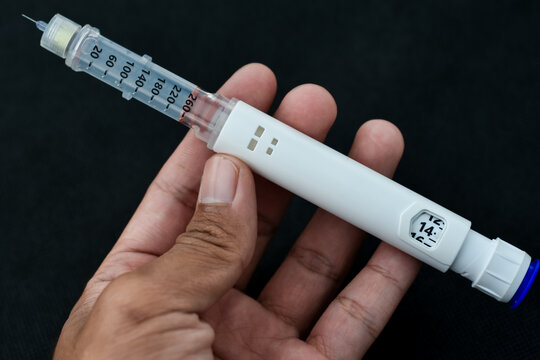 Insulin pen isolated on black background. Medical devices are used for self-injection for the treatment of diabetes. World diabetes day and health care concept.
