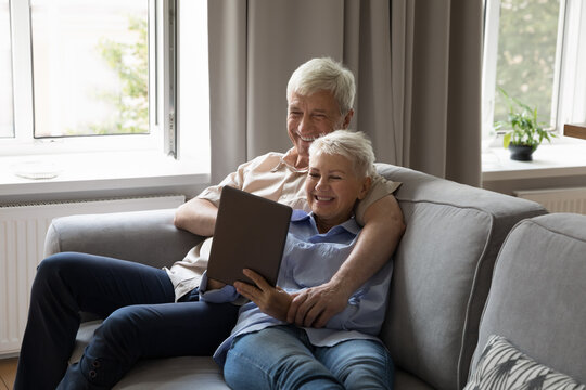 Relaxed Happy Affectionate Middle Aged Family Couple Using Digital Computer Tablet Applications, Buying Tickets Online Planning Travel Vacation, Shopping In Internet Store Or Communicating Distantly.