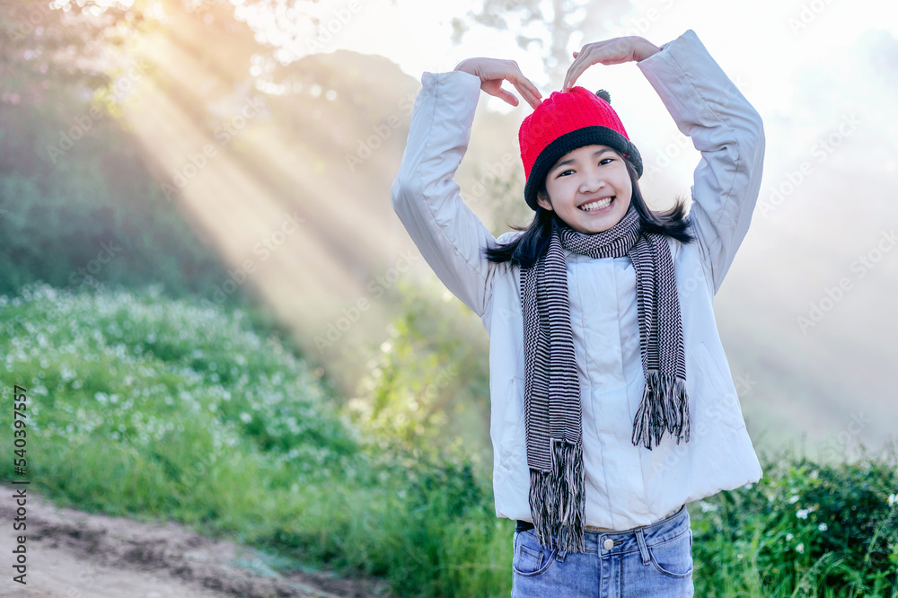 Wall mural Happy smile single teenager girl with red hat in a park with a warm yellow light and nature background