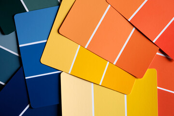 Generic color swatches scattered on a table. Swatches are in various autumnal shades of yellows and oranges, with complimentary blues as well. Fall color schemes. Interior design color pallet.