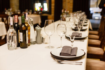 Table setting with sparkling wineglasses, plates with napkins and cutlery on table, copy space. Place set at wedding reception. Table served for wedding banquet in restaurant.