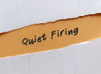 Torn paper on beige background with handwriting Quiet Firing - refers to employers who treat...