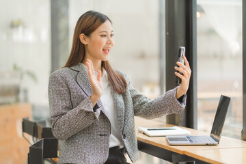 Asian businesswoman in formal suit in office happy and cheerful during using smartphone and working