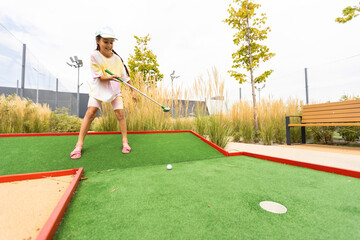 Beautiful little girl playing mini Golf - obrazy, fototapety, plakaty
