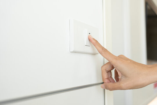 woman turning off light switch in a home