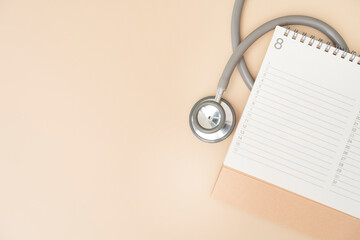 Top view of stethoscope and calendar on the brown background, schedule to check up healthy concept