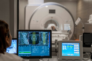 the radiology technician in the cabin stands next to his patient in the CT MRI scanner or computed tomography, the other technician examines the medical images. magnetic resonance imaging machine
 - obrazy, fototapety, plakaty