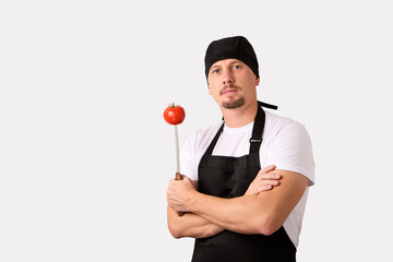 Chef cook holds a knife with tomato on white background