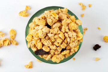 Granola bowl with raisins, nuts. Homemade crunchy granola scattered on white background, top view.